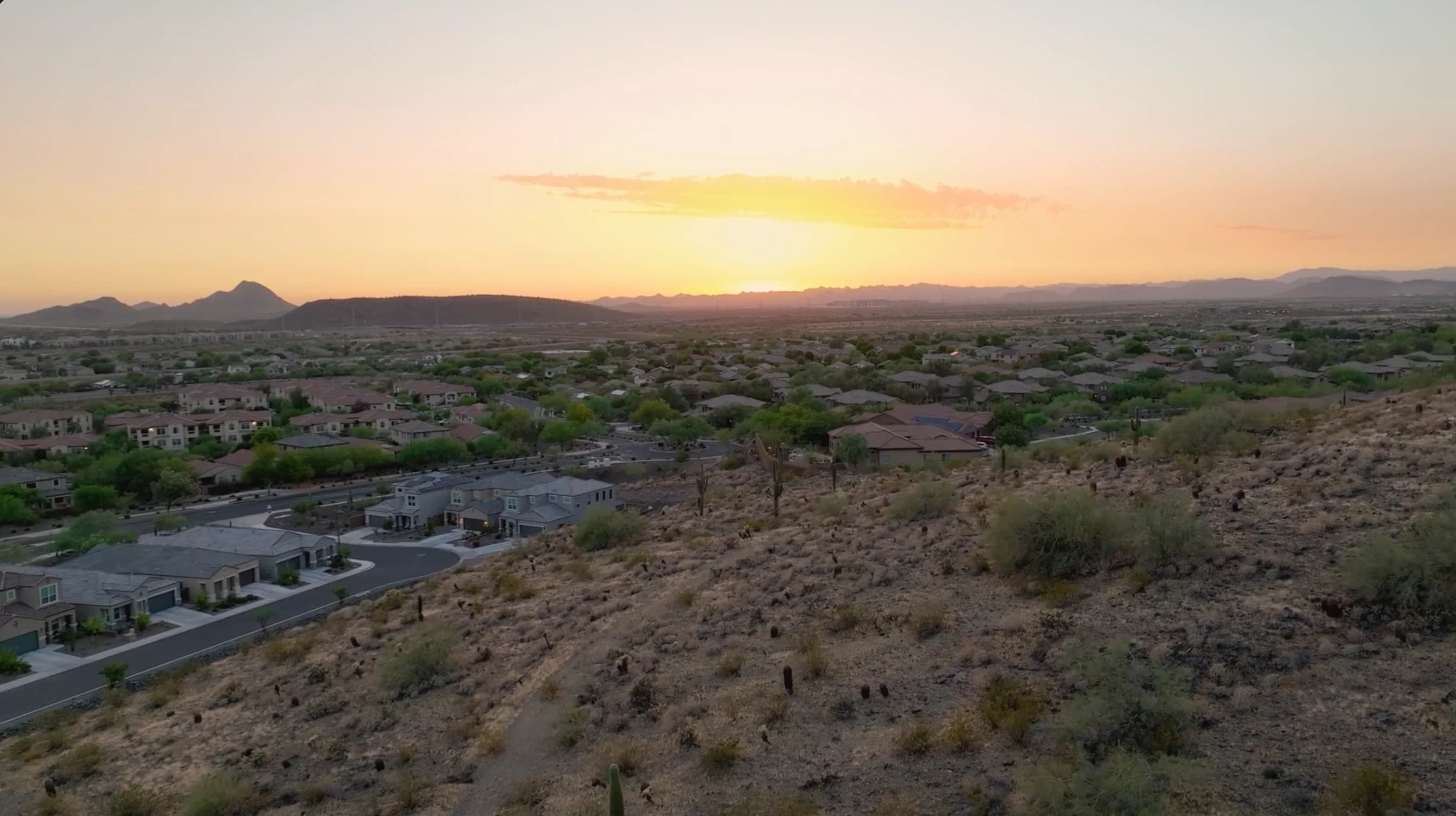 Residential neighborhoods and desert hills in warm evening light.