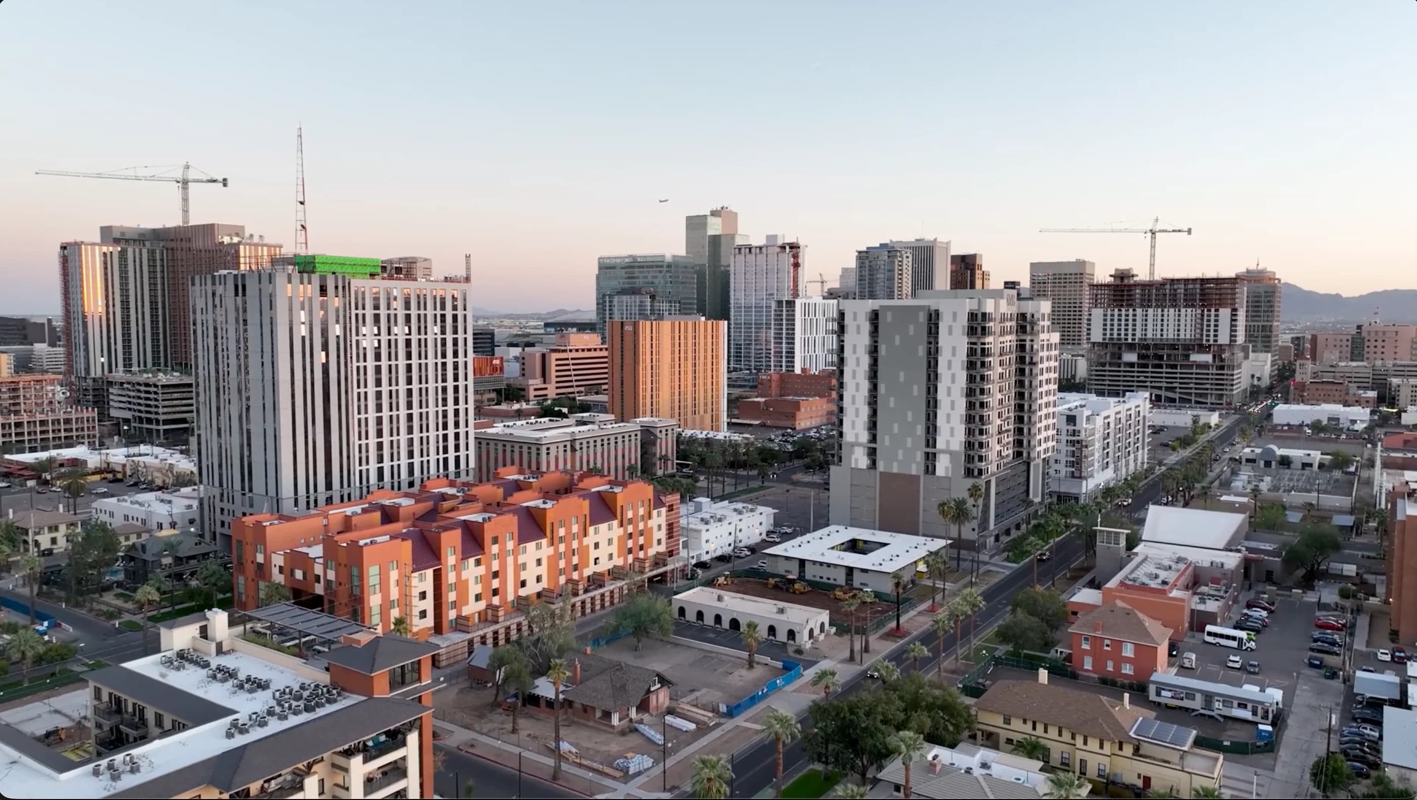 City skyline with residential buildings, streets, and construction cranes.