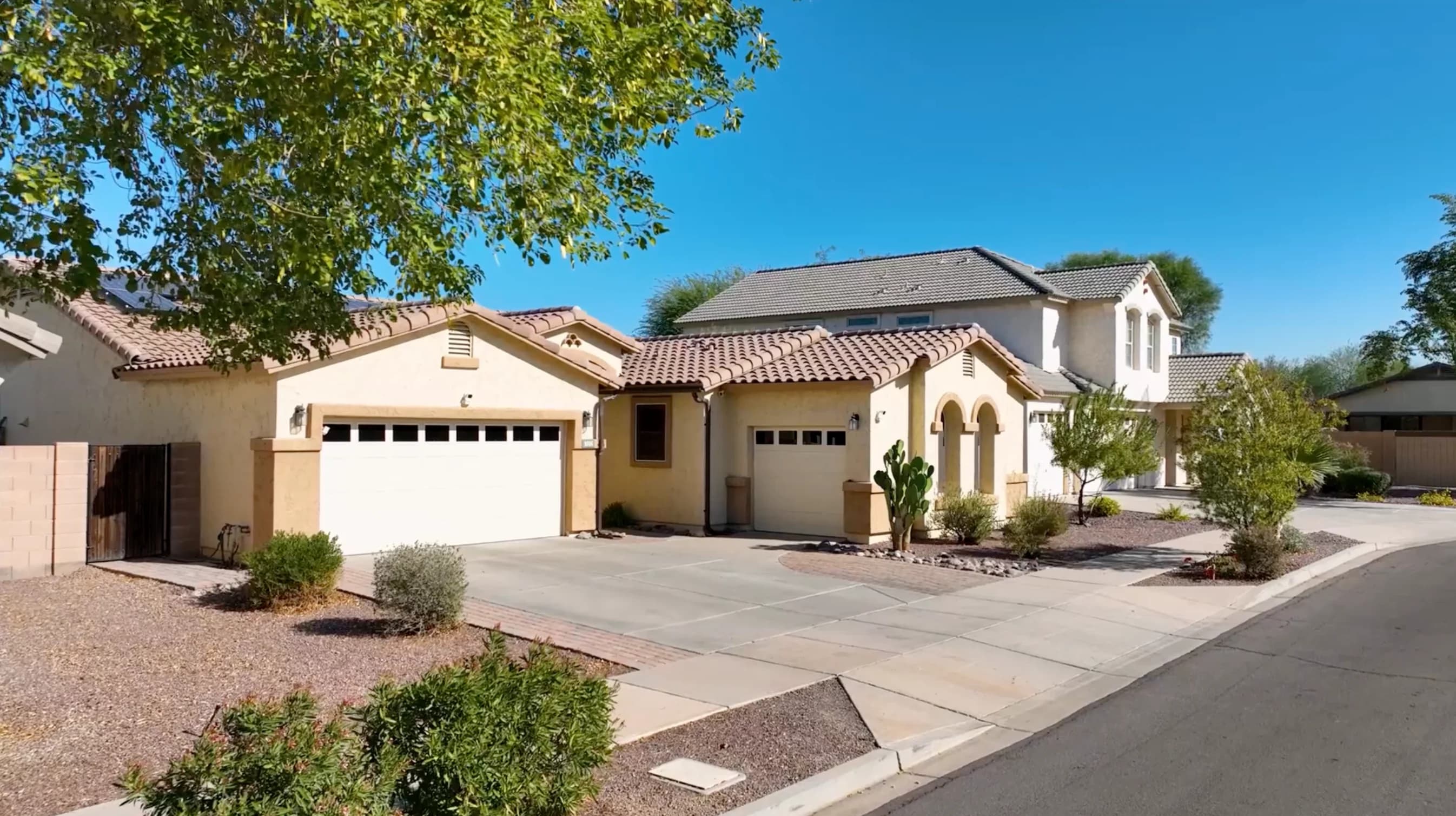 Stucco homes with tiled roofs, driveways, and desert landscaping.