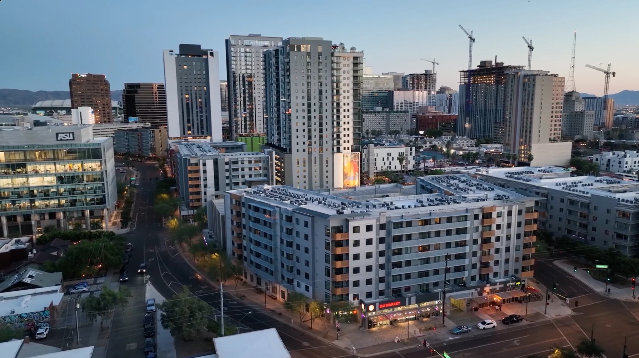 Urban neighborhood with apartments, offices, and a street intersection at dusk.