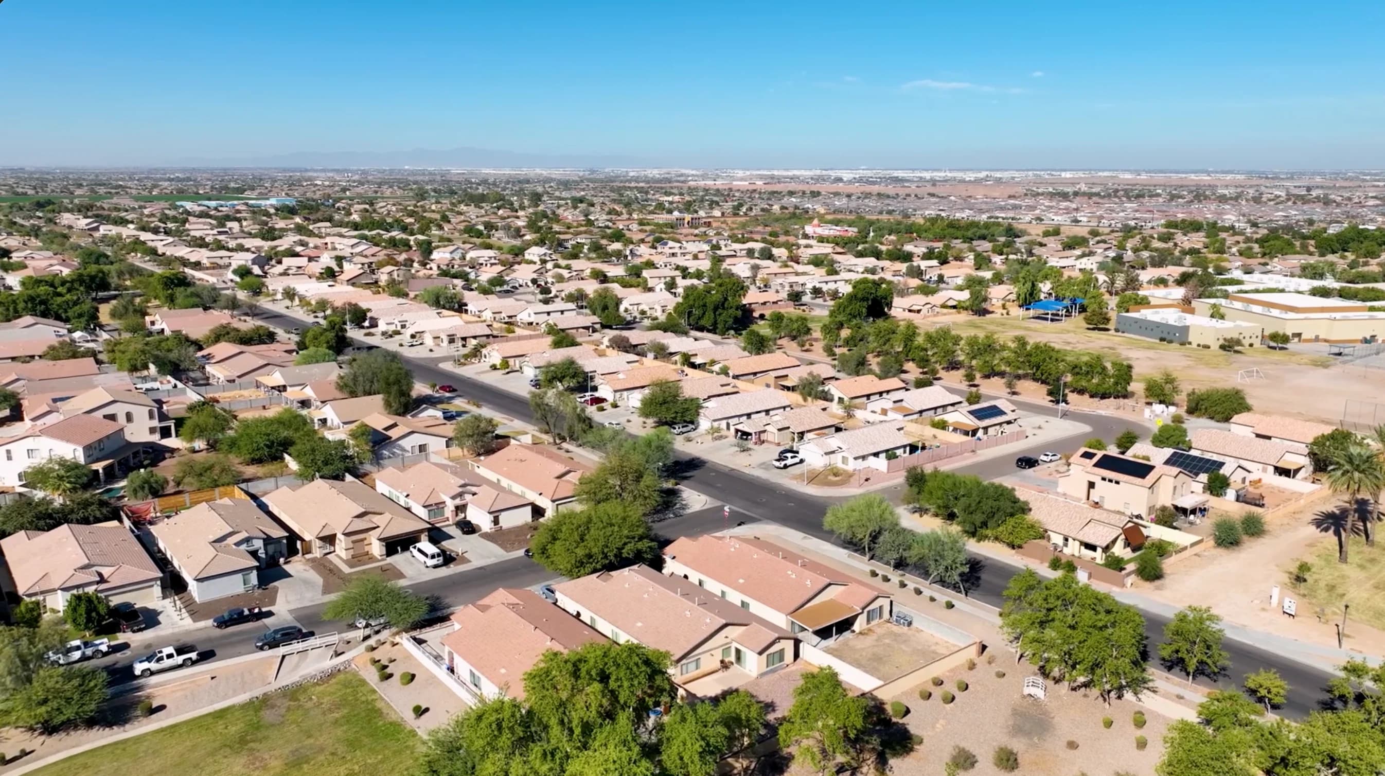 Aerial view of a residential neighborhood with tiled roofs and tree-lined streets.